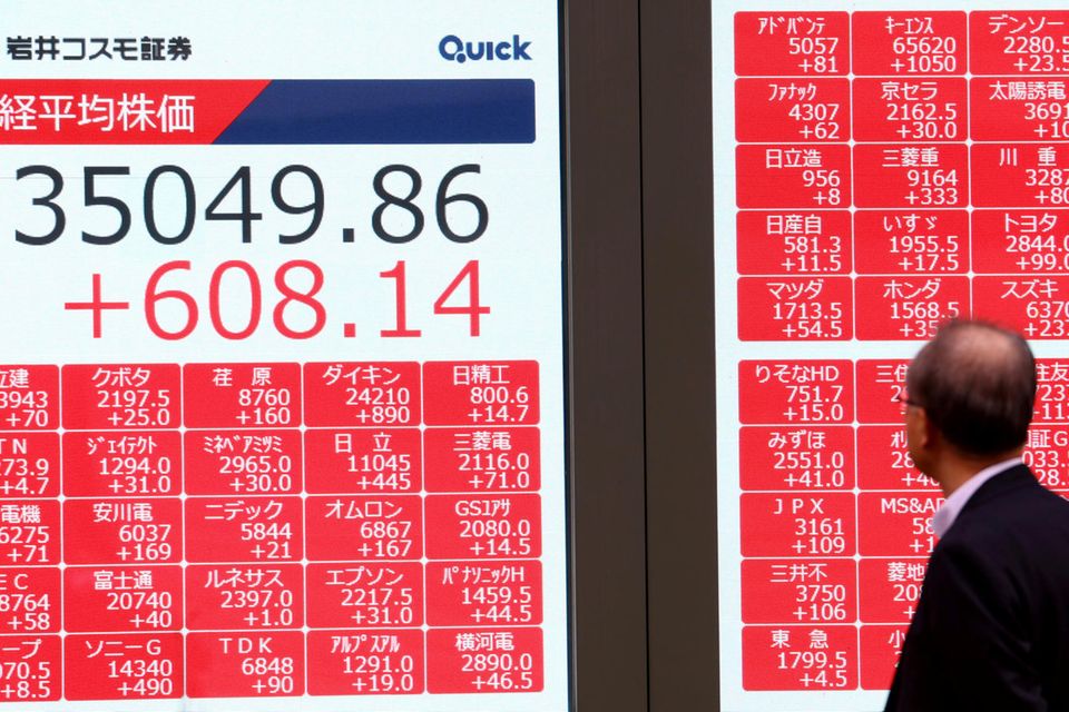 Ein Mann betrachtet in Tokio einen Bildschirm auf dem Aktienkurse zu sehen