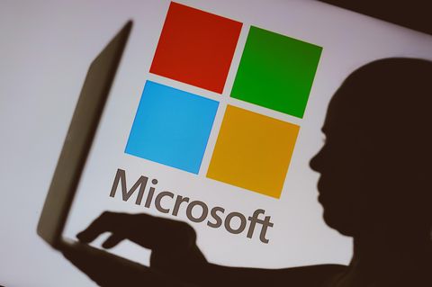Ein Mann mit Laptop vor einem Microsoft-Logo