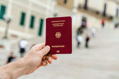 Eine Person hält einen Reisepass der Bundesrepublik Deutschland hoch