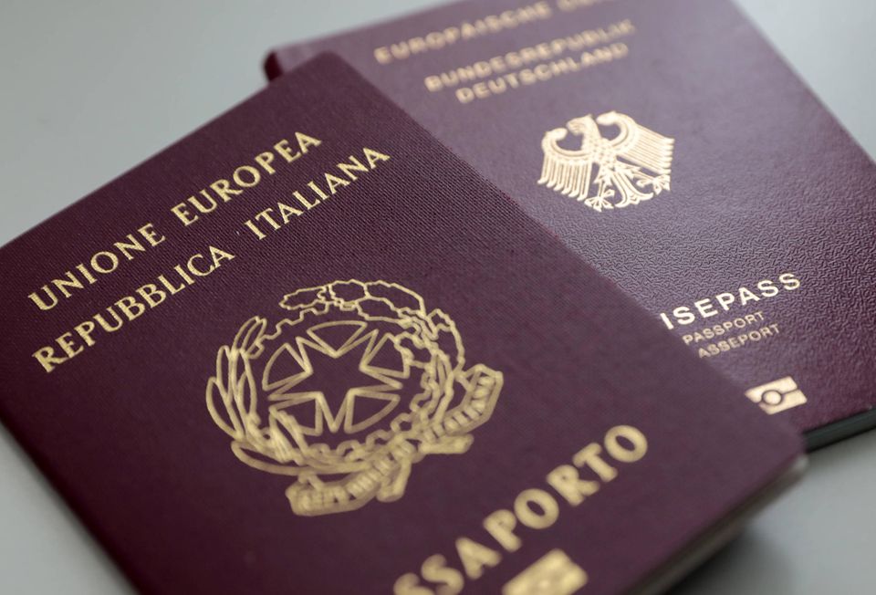 Im Vordergrund liegt ein italienischer Reisepass, dahinter ein deutsches Ausweisdokument