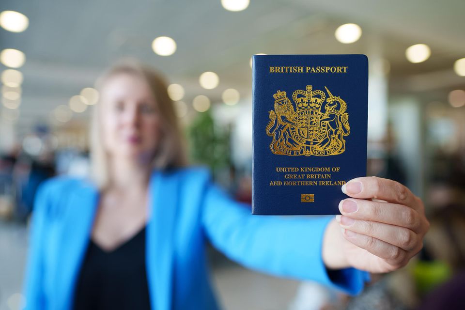 Eine Frau hält einen britischen Reisepass in die Höhe
