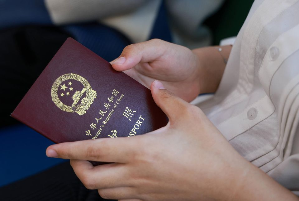 Ein Mädchen hält einen chinesischen Reisepass in den Händen