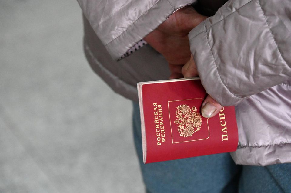 Eine Frau hält ihren russischen Pass für eine Kontrolle bereit