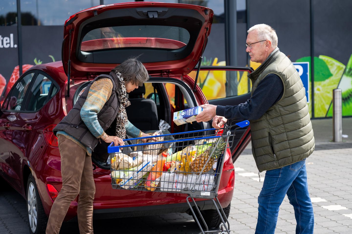 Ein älteres Ehepaar verstaut den Einkauf im Auto