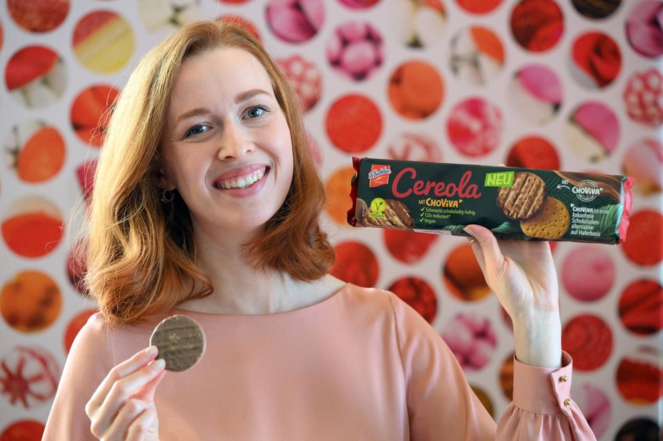 Ein Model präsentiert auf der Internationalen Süßwarenmesse Choviva-Kekse von DeBeukeler