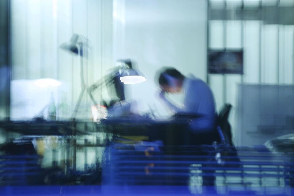 Ein Mann arbeitet außerhalb der normalen Bürozeiten an seinem Schreibtisch