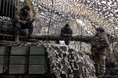 Ukrainische Soldaten unterhalten sich, während einer sich auf das Geschütz eines Panzers stützt