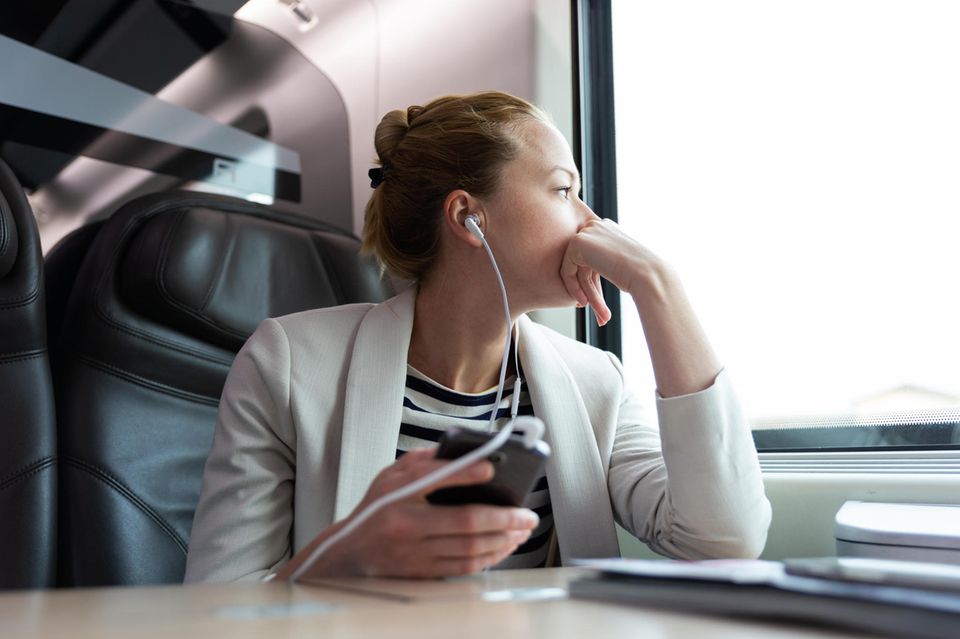 Eine Geschäftsreisende führt ein Telefonat im Zug