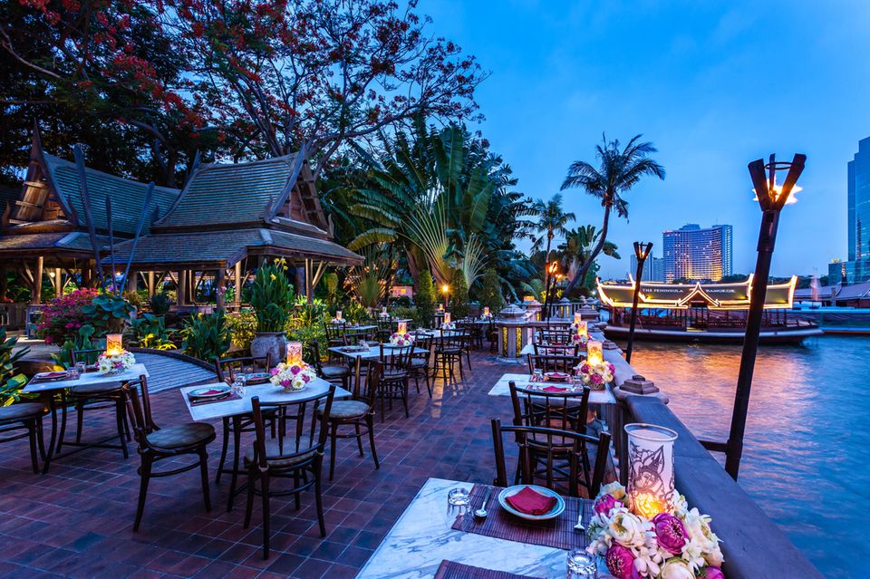 Paradiesisch Speisen: Das Hotelrestaurant „Thiptara“ bietet eine Thai-Küche unter Palmen direkt am Ufer. Die Skyline von Bangkok und der Sternenhimmel sind gratis