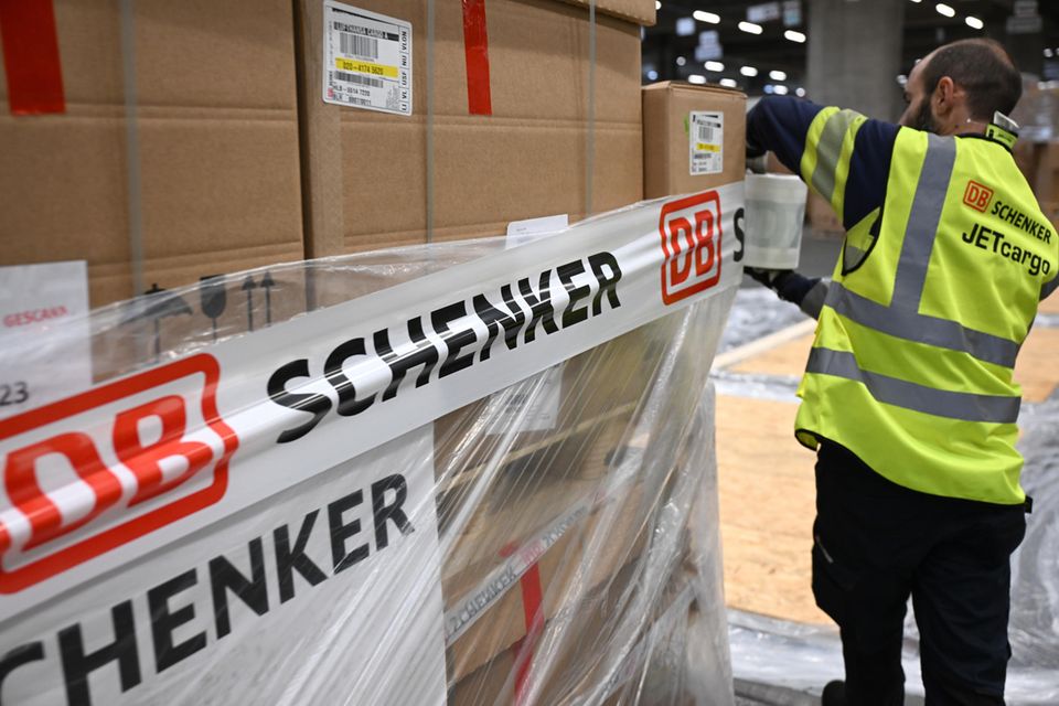 Ein Mitarbeiter der DB Schenker Jetcargo bringt in der Luftfrachthalle in der Cargo City Süd am Flughafen Frankfurt Klebeband an einer Palette an