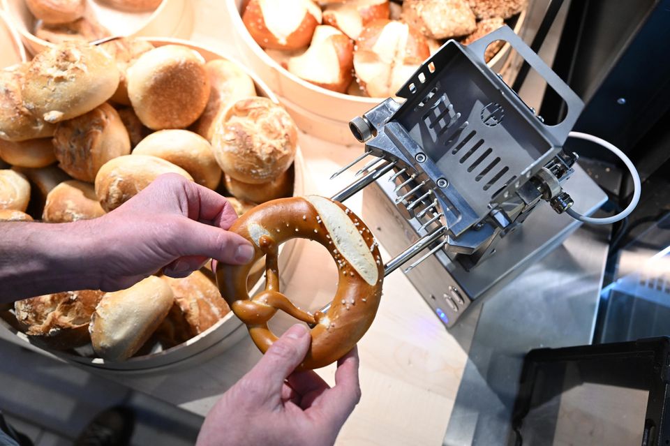 Eine Brezel wird mit einer neu erfundenen Maschine mit Butter befüllt
