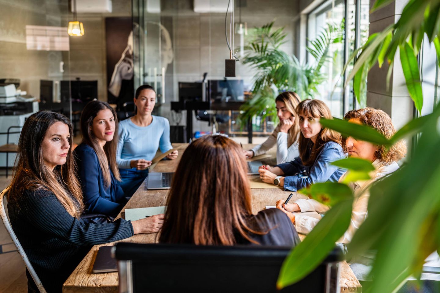 Team und Führungskräfte sitzen an einem Tisch im Büro