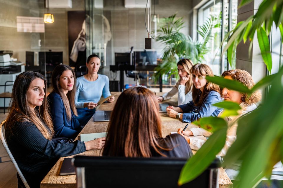Team und Führungskräfte sitzen an einem Tisch im Büro