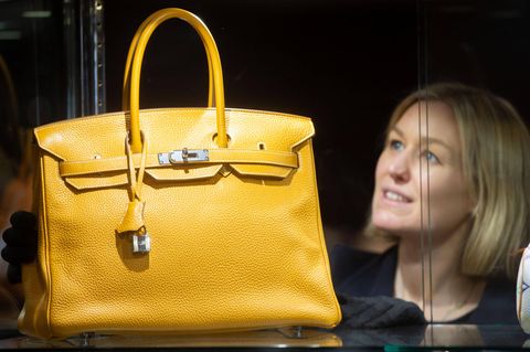 Eine Hermès-Mitarbeiterin präsentiert eine gelbe Handtasche des Modells Birkin