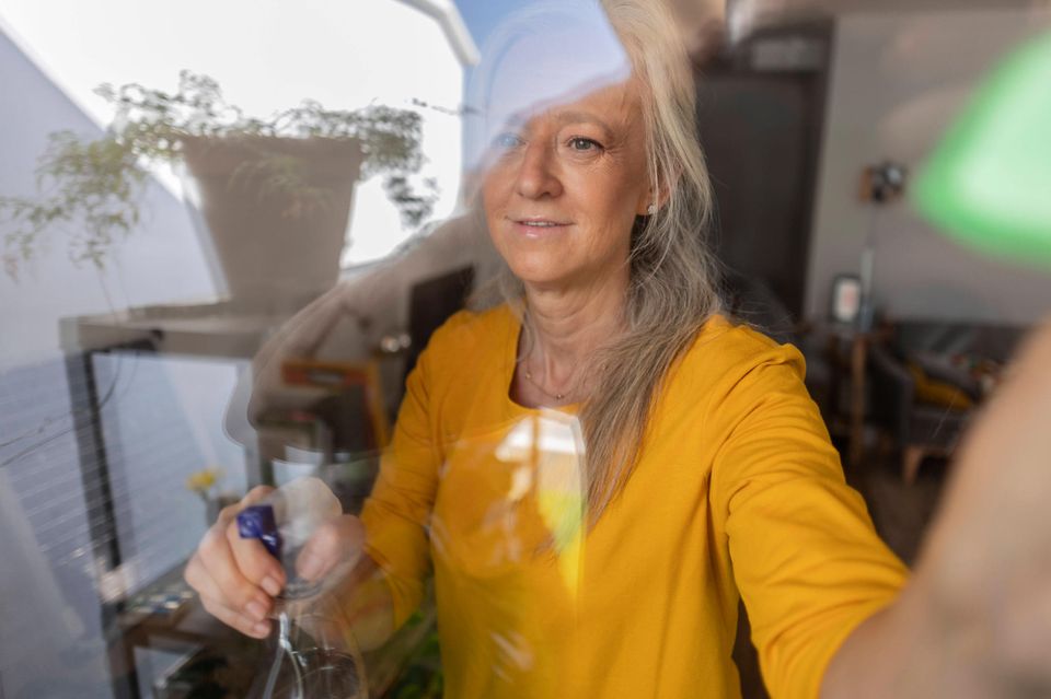 Eine Frau putzt eine Fensterscheibe