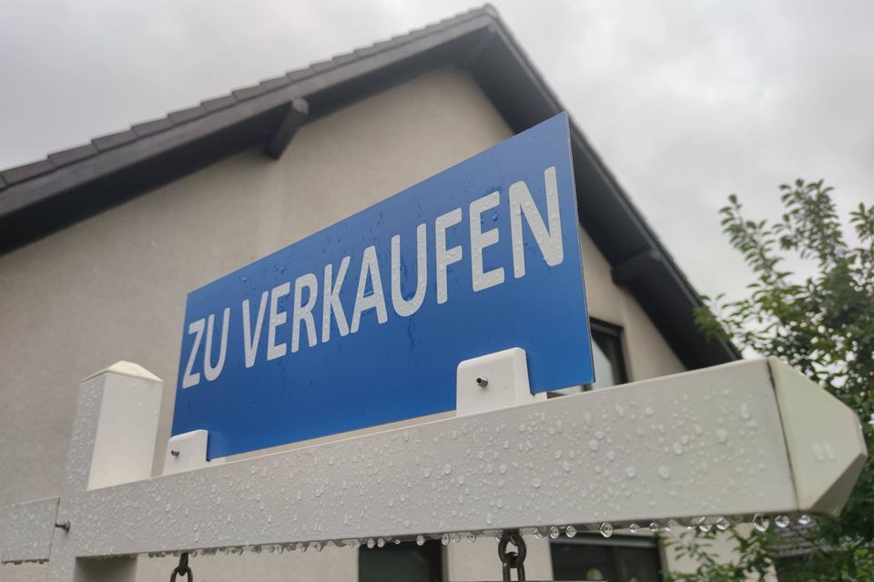 Vor einem Haus steht ein Zu-Verkaufen-Schild