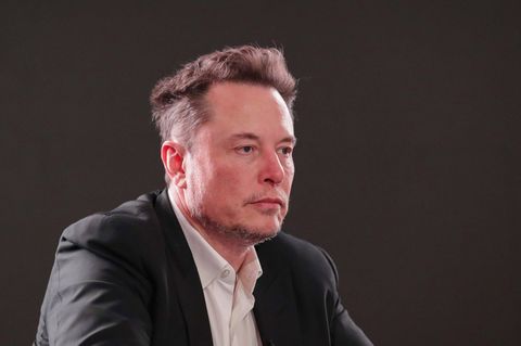 Elon Musk, vor dunklem Hintergrund, blickt nach rechts