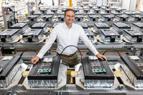 Ein Mann mit weißem Hemd steht in einer Fabrik für Batteriezellspeicher