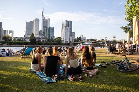 Menschen sitzen entspannt am Mainufer in Frankfurt