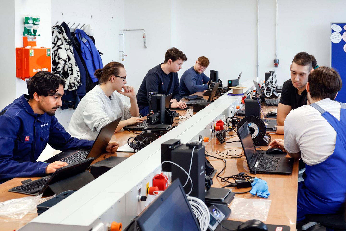 Auszubildende an Tischen mit Computern und Kabeln