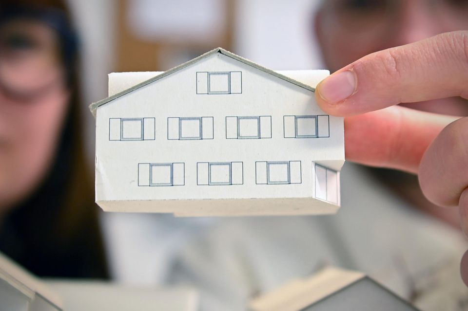 Modell eines Hauses aus Papier in der Hand eines Architekten