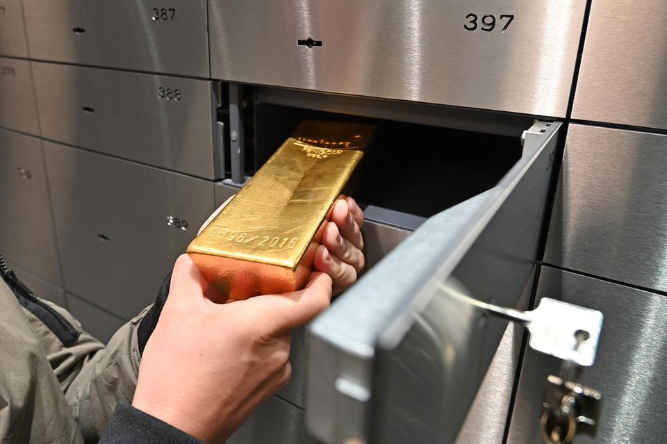 Ein Mann schiebt einen Goldbarren in ein Bankschließfach