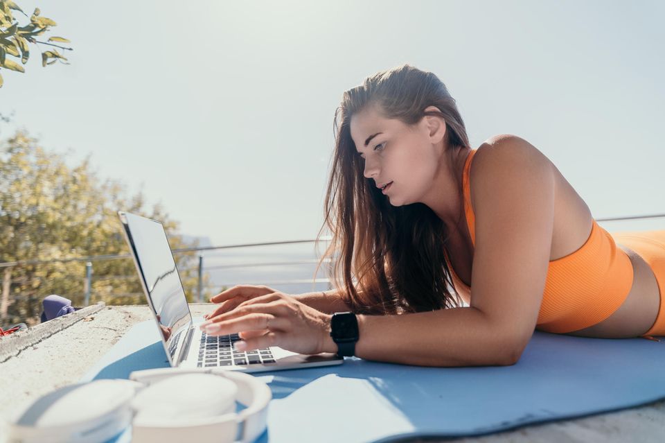 Junge Frau arbeitet am Laptop nahe des Meeres