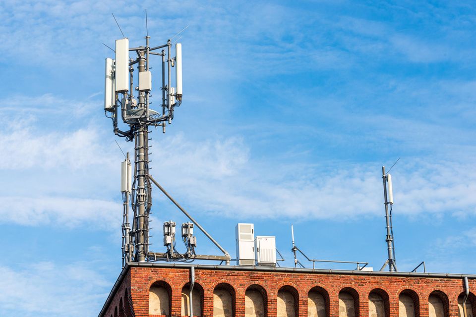 Antenne für den mobilen Funkverkehr auf dem Dach eines Gebäudes vor blauem Himmel