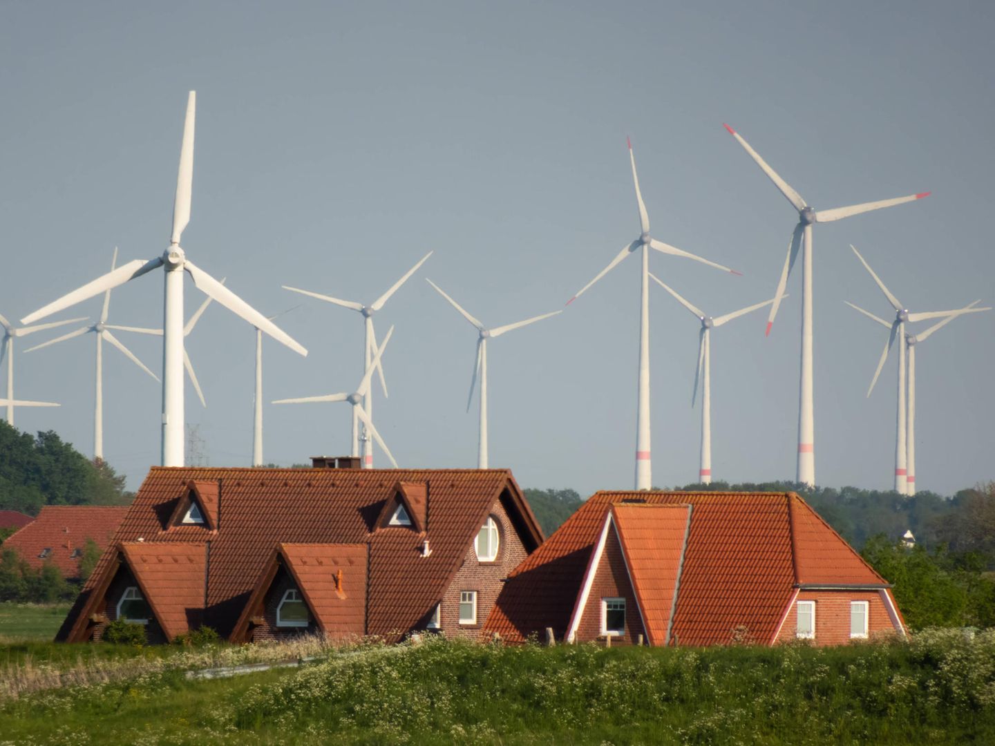 Wohnhäuser und Windräder hinter dem Deich bei Nessmersiel in Ostfriesland