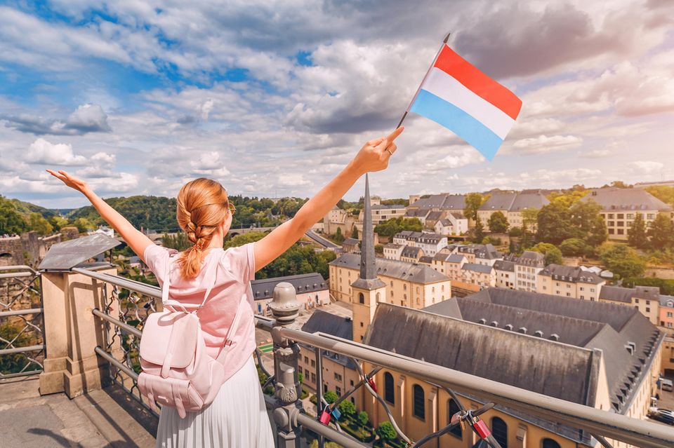 Eine Frau jubelt mit einer fahne Luxemburgs in der Hand