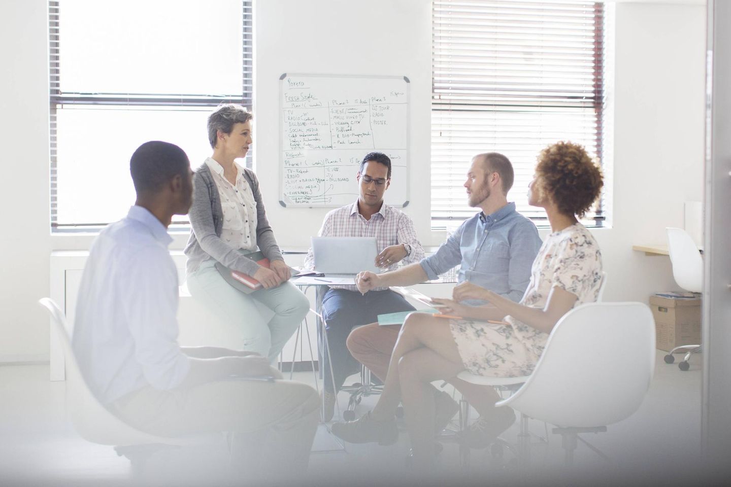 Zwei Frauen und drei Männer bei einem Meeting im Büro