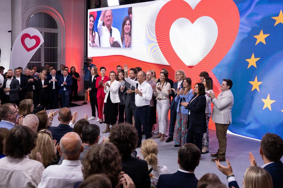 Polens Ministerpräsident Donald Tusk steht auf einer Bühne umgeben von Anhängern und winkt ins Publikum