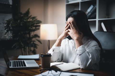 Eine Arbeitnehmerin sitzt gestresst vor dem Laptop