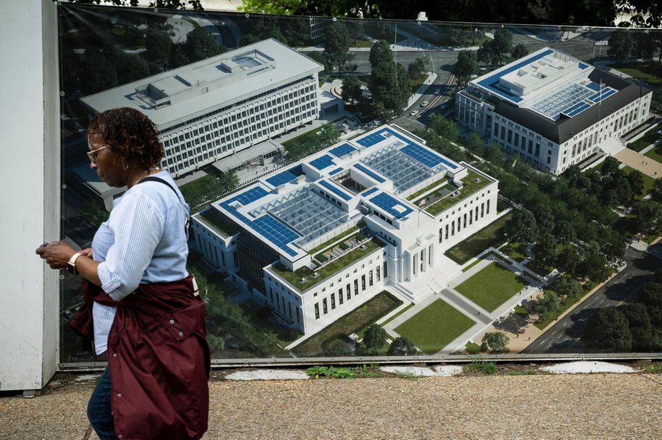 Eine Frau läuft an einem Plakat vorbei, auf der die US-Notenbank Fed abgebildet is