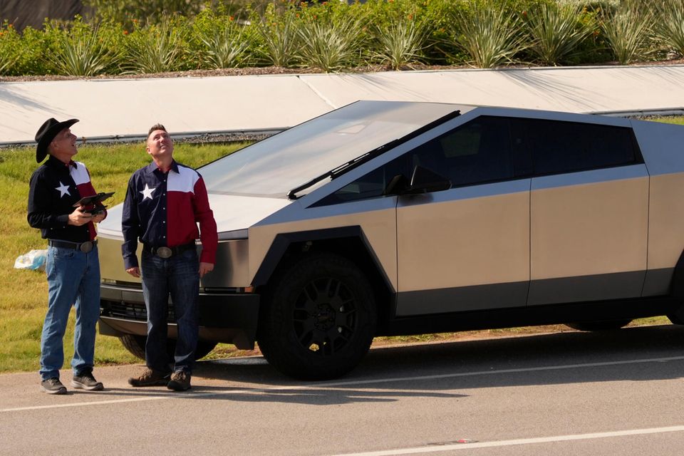 Vor der Hauptversammlung von Tesla stehen zwei Männer neben einem Cybertruck