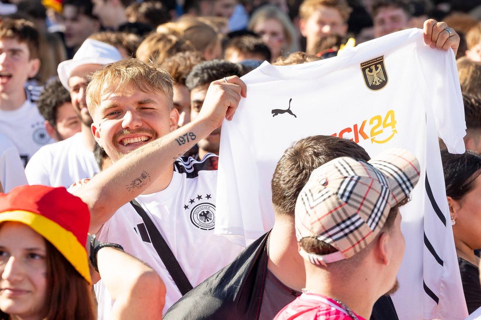 Ein Fußball-Fan hält auf der Fanmeile in Frankfurt an Check24-Trikot in die Höhe