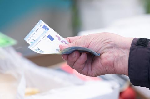 Eine Frau bezahlt mit Bargeld auf einem Wochenmarkt ihre Einkäufe