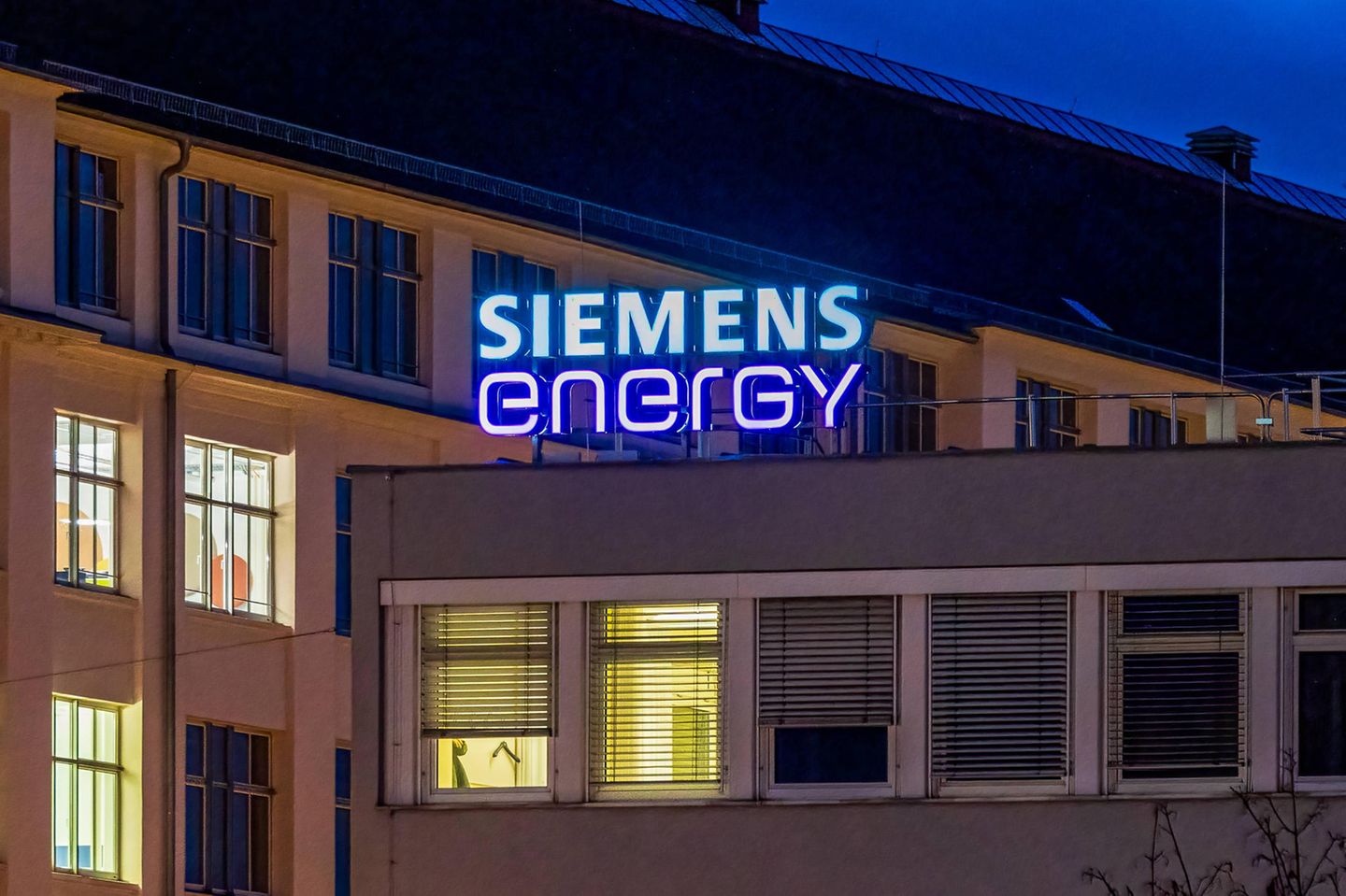 Beleuchteter Schriftzug von Siemens Energy an einem Firmengebäude bei Nacht