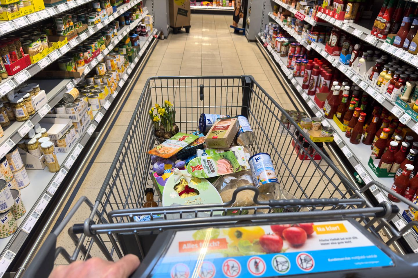 Ein Mann schiebt einen Einkaufswagen durch einen Supermarkt