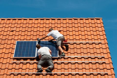 Installateure bringen Solarpanele auf einem Hausdach an