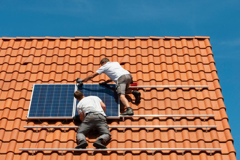 Installateure bringen Solarpanele auf einem Hausdach an