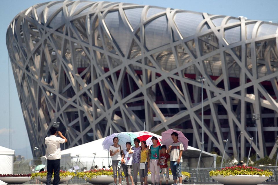 Eine Besuchergruppe posiert vor dem Olympiastadion in Peking für ein Foto