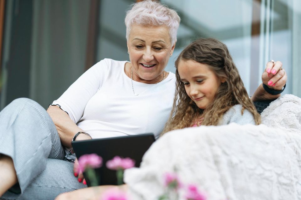 Oma und Enkelin schauen aufs Tablet