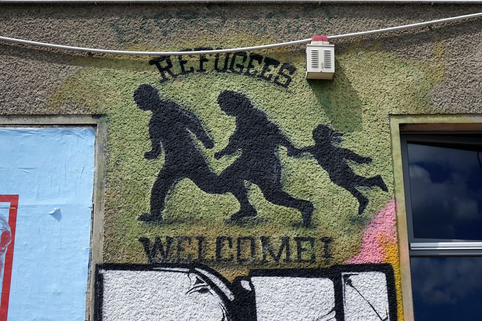 An einem Gebäude befindet sich ein Graffiti mit dem Schriftzug „Refugees welcome“