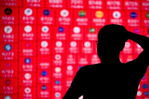 Diese Illustration zeigt eine menschliche Silhouette vor einem Bildschirm mit den Logos von Börsenkonzernen in Ankara