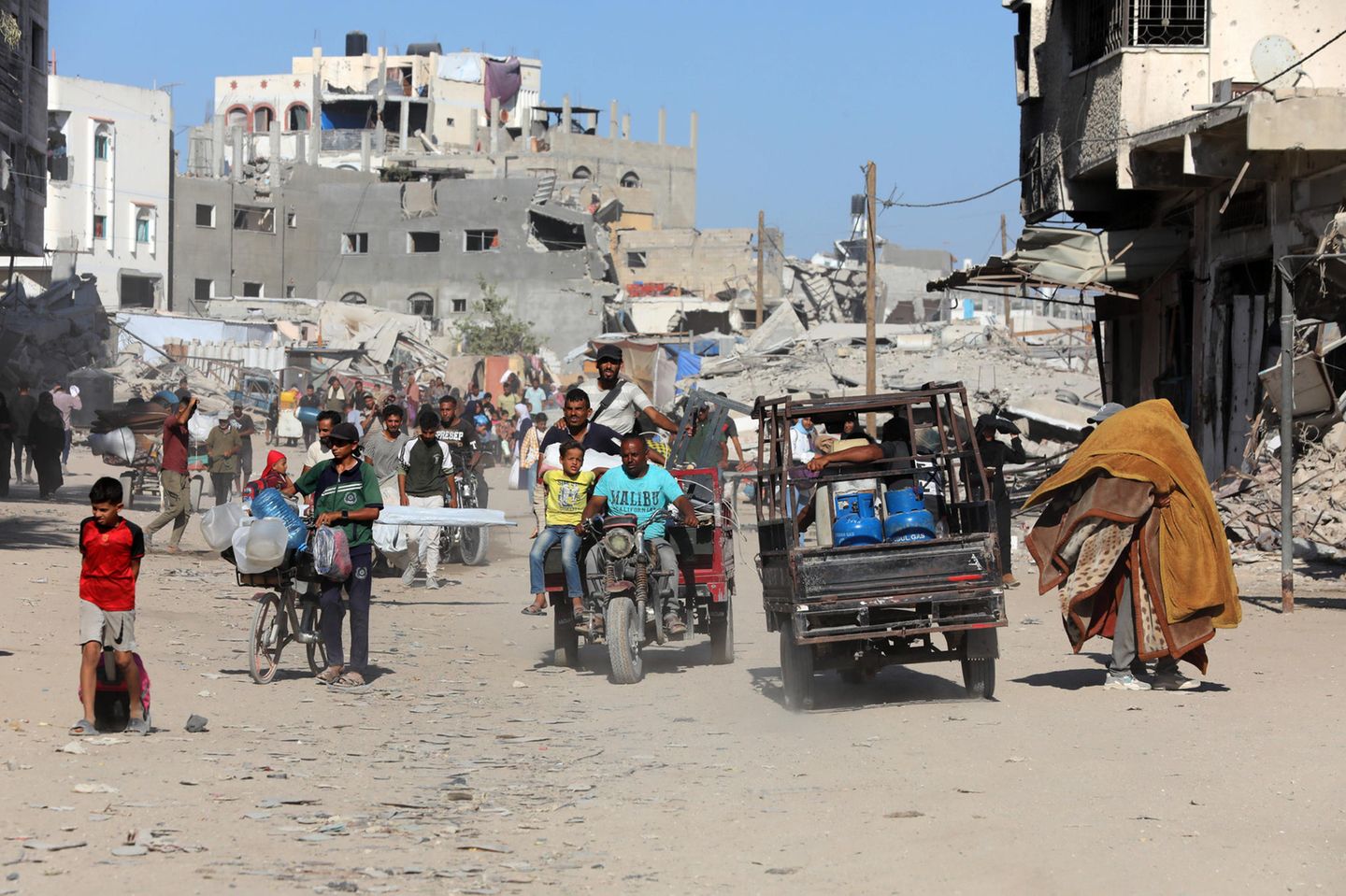 Szene mit Menschen und zerstörtem Haus in Gaza