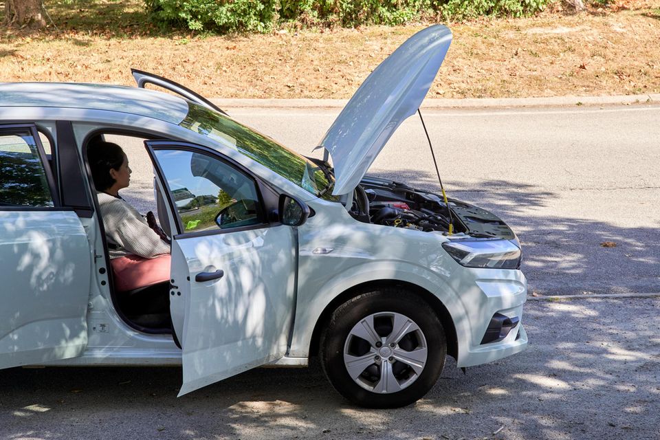 Eine Frau sitzt in einem kaputten Auto