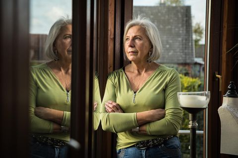 Eine Rentnerin schaut gedankenverloren aus dem Fenster