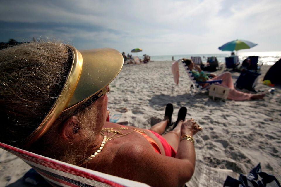 Eine Rentnerin liegt auf einer Sonnenliege am Strand