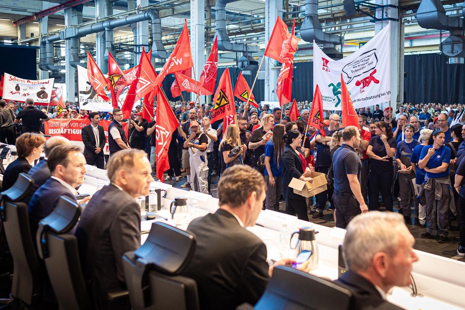 Mitarbeiter protestieren vor Beginn einer Betriebsversammlung in einer Halle im VW-Werk